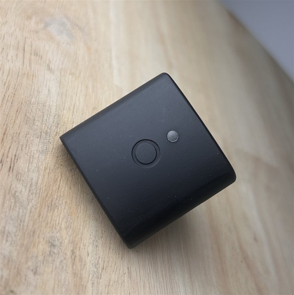 A LEVEL Inez sensor, a small black square unit with a status LED, a button, a USB-C charging port, and a reset button